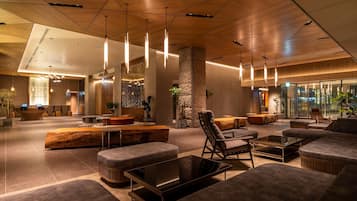 A modern lobby with seating areas, a reception desk, and a large window providing a view of the city.