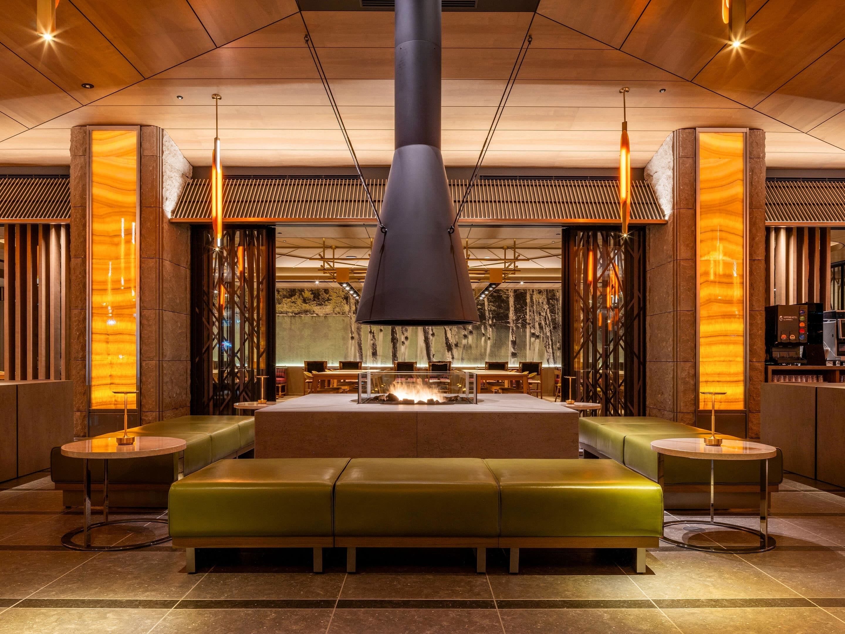 A modern interior with a central seating area, a fireplace, and a coffee machine.