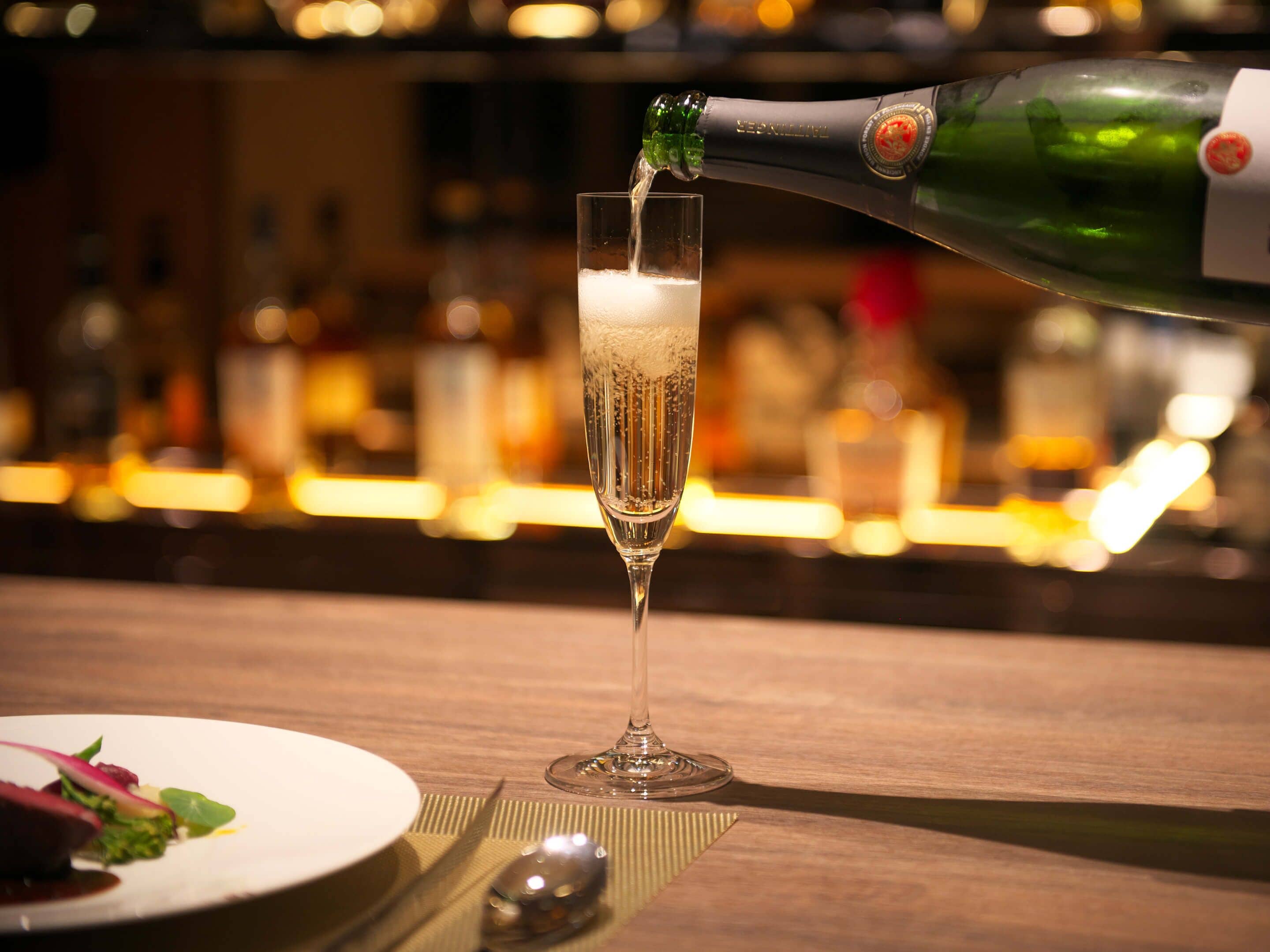 A champagne bottle being poured into a glass.