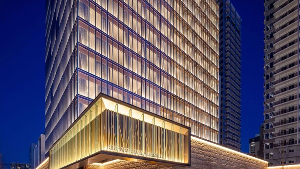 Un hotel moderno con fachada de vidrio, un área exterior cubierta con asientos y suelo cubierto de nieve.