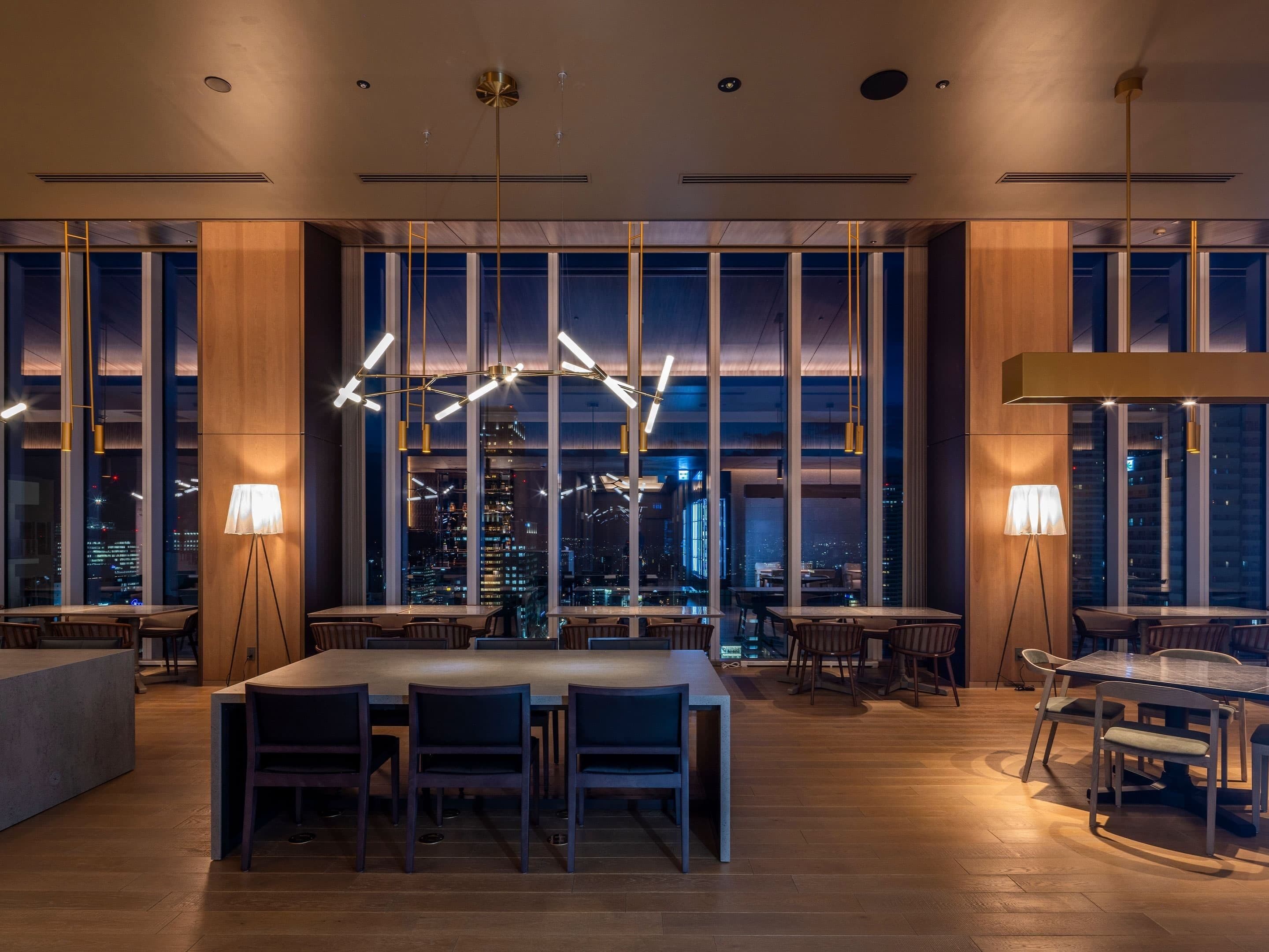 A modern dining area with high ceilings, large windows, and contemporary lighting fixtures.