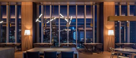 A modern dining area with high ceilings, large windows, and contemporary lighting fixtures.