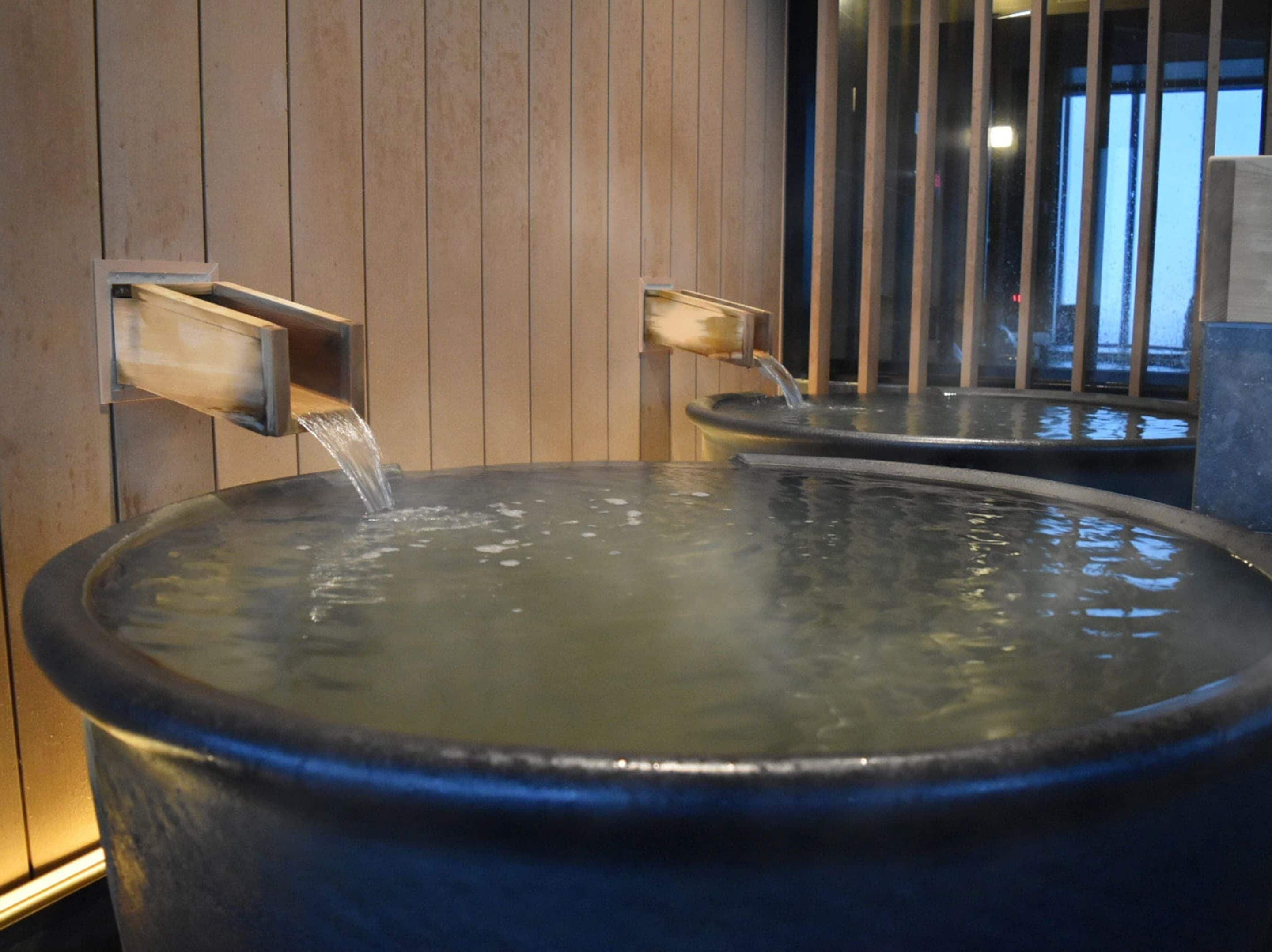 A hot spring bath with two faucets, wooden paneling, and a large basin.