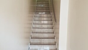 Una escalera con barandilla y pared de color claro.