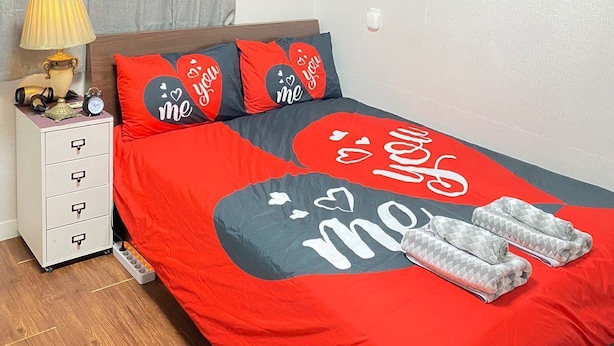Een slaapkamer met een bed, nachtkastje, lamp, verwarming en een airconditioning.