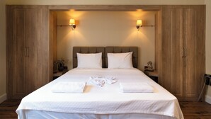 A hotel room with a large bed, wooden wardrobe, and two wall-mounted lamps. - Level Suites (Istanbul)