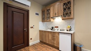 A compact kitchen with wooden cabinets, a white countertop, and a built-in dishwasher. - Level Suites (Istanbul)