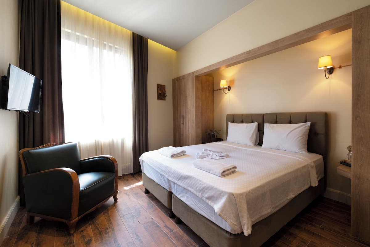 Ein Hotelzimmer mit einem großen Bett, einer Sitzecke, einem Flachbildfernseher und Holzboden.