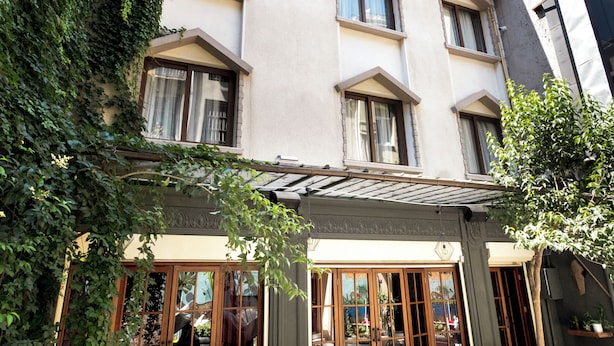 A building with a covered outdoor seating area, wooden furniture, and potted plants. - Level Suites (Istanbul)