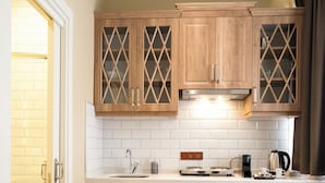 A compact kitchen with wooden cabinets, a white countertop, a coffee maker, and a dishwasher. - Level Suites (Istanbul)