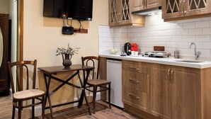 A kitchen with wooden cabinets, a dining table with chairs, a TV mounted on the wall, and a coffee maker on the counter. - Level Suites (Istanbul)