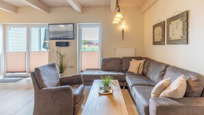 Een woonkamer met een hoekbank, een salontafel en een televisie.