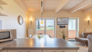 Een moderne keuken met een centraal eiland, houten kasten en een eethoek met een tafel en stoelen.