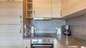A modern kitchen with wooden cabinets, a stainless steel stove, and a coffee maker.