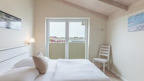 Een slaapkamer met een bed, een stoel, een raam en een schilderij aan de muur.