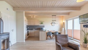 Een moderne keuken met houten kastjes, een centraal eiland en een eethoek met stoelen en een tafel.
