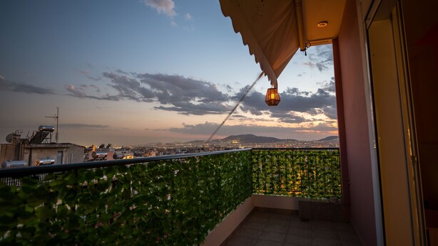 A balcony with a view of the cityscape at dusk, featuring a railing, a hanging light fixture, and a tiled floor. - Athens Acropolis View Penthouse-center of Athens (Athens)