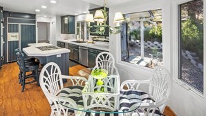 A modern kitchen with a central island, white chairs, and a dining table. - Lakefront Splendor:Spectacular Lakefront Property w/Private Dock! Pool Table + Foosball Table! Spacious Outdoor Deck! Patio & Yard w/Firepit! (Big Bear Lake)