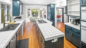 Una cocina moderna con una isla central, suelo de madera y armarios oscuros.