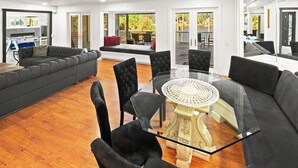 Una sala de estar moderna con una mesa de centro de vidrio, sillas tapizadas en negro y un sofá gris.