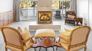 Un salón espacioso con chimenea, asientos cómodos y ventanas amplias que ofrecen vistas al exterior.