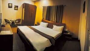 A hotel room with a bed, a desk, two chairs, and a wardrobe. - Shavin Residency Wardha Maharashtra (Wardha)