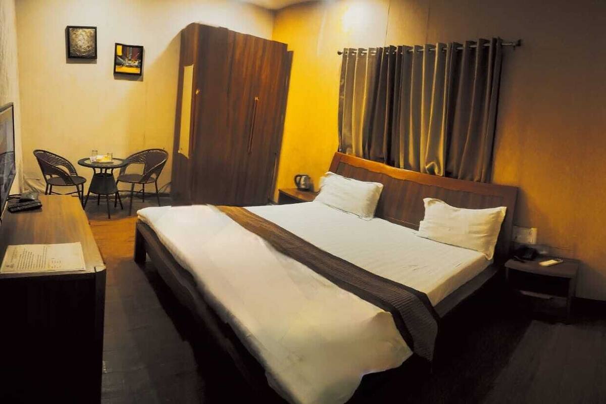 A hotel room with a bed, a desk, two chairs, and a wardrobe.