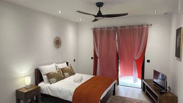 A bedroom with a bed, a nightstand, a television, and a ceiling fan.