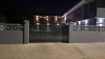 A gated entrance to a modern building with a flat roof and multiple windows.