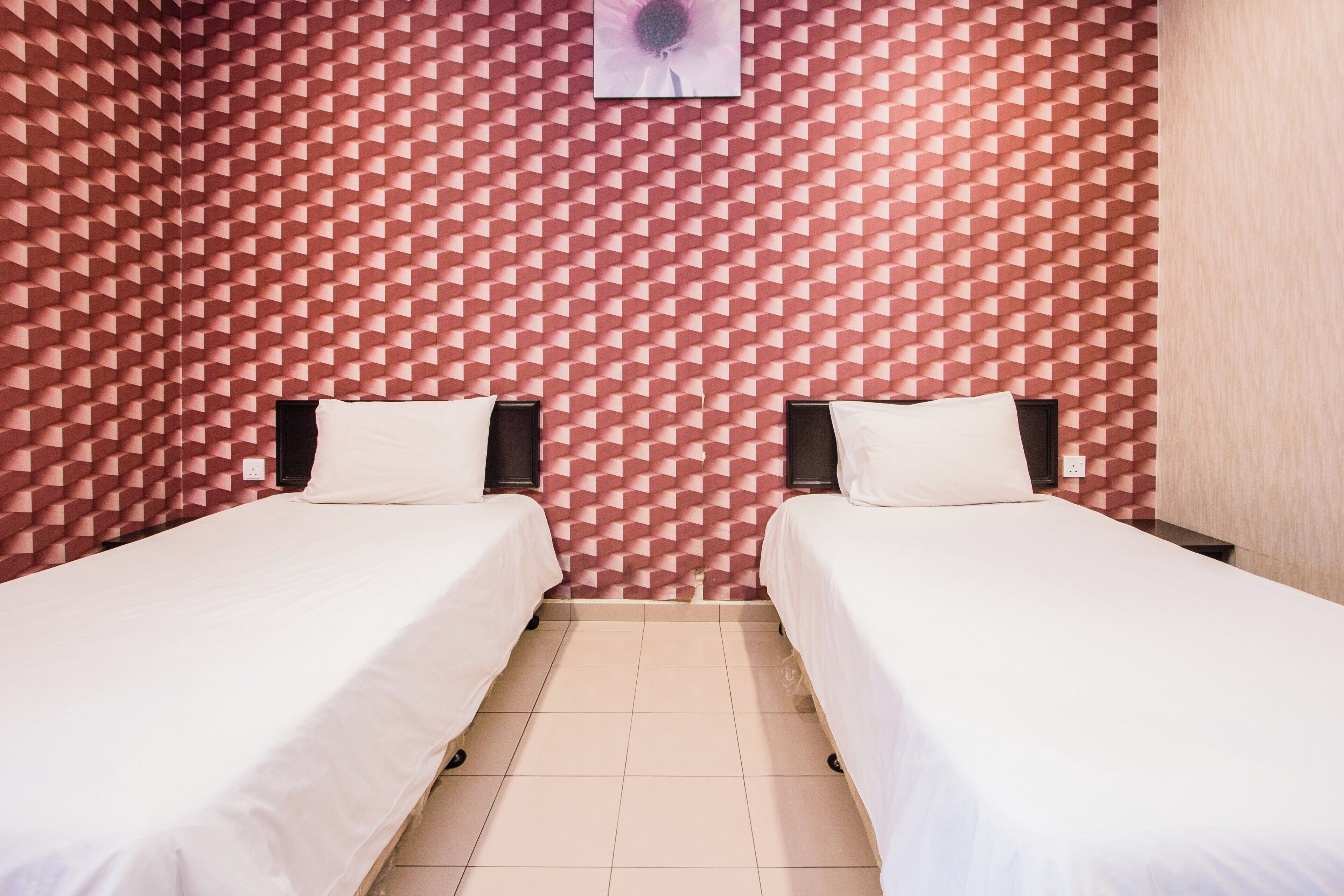Une chambre avec deux lits, un mur orné d’un motif et un plancher de couleur claire.