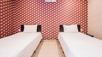 Une chambre avec deux lits, un mur orné d’un motif et un plancher de couleur claire.