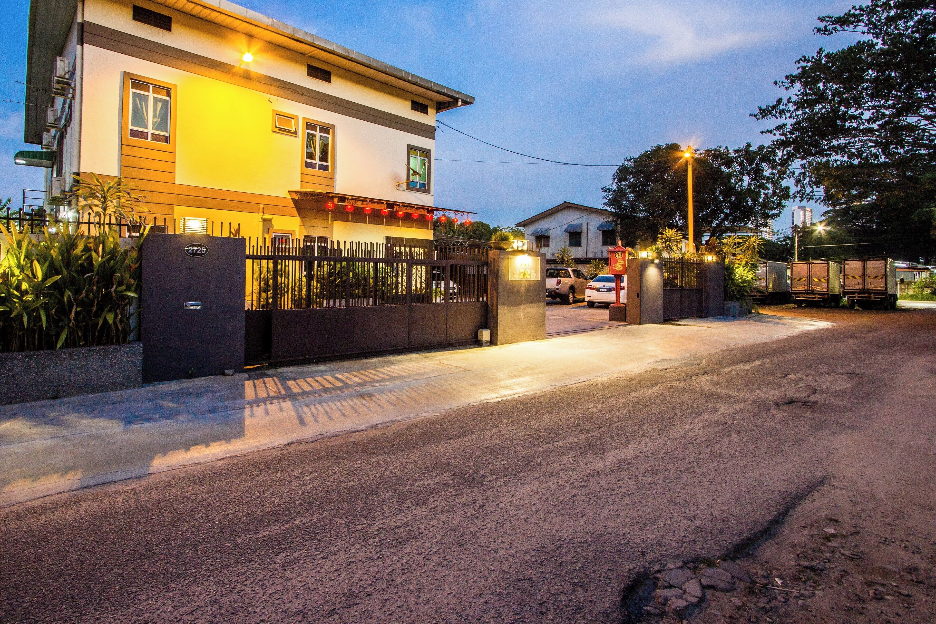 A gated residential area with a well-lit entrance, a paved driveway, and a parked vehicle.