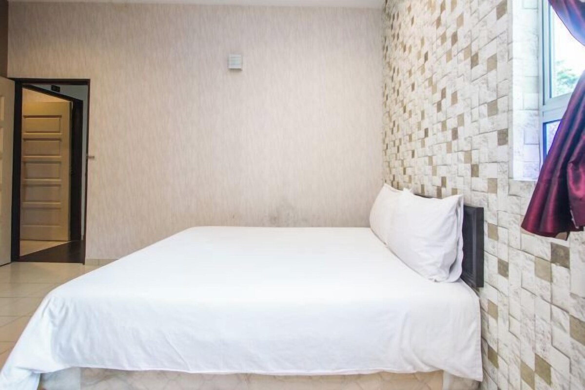 A neatly made bed in a room with a tiled wall and a door leading to another room.
