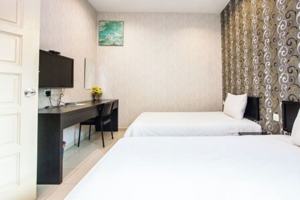 Une chambre d’hôtel avec deux lits, un bureau avec une télévision et un mur décoré d’un motif.