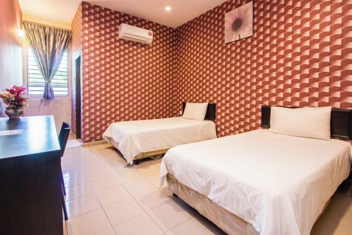 A hotel room with two beds, a desk, and a window with curtains.