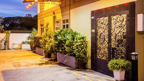 A building entrance with a decorative gate, potted plants, and a parking meter. - Value Inn Homestay by uBook (Butterworth)