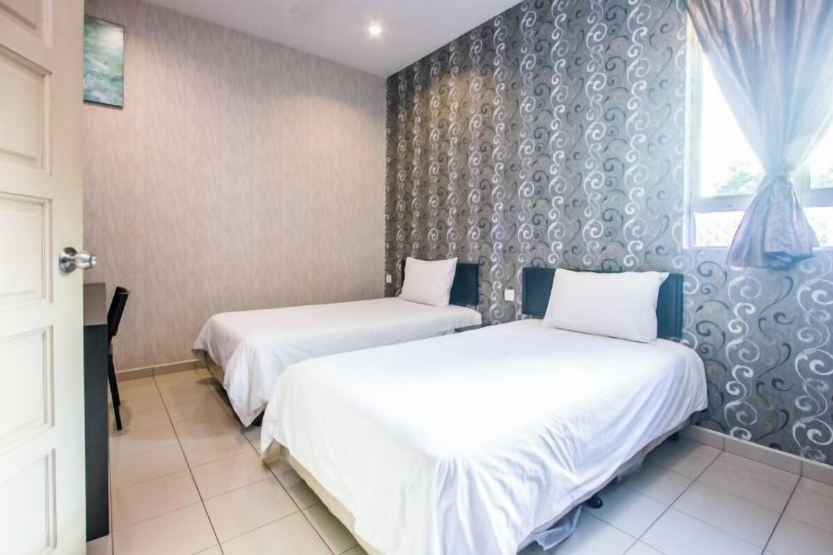A hotel room with two single beds, a chair, a door, and a patterned wall.
