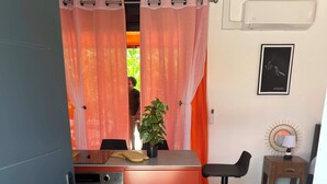 A compact kitchen with a red countertop, a stove, and a sink. There is a small wooden stool and a wall-mounted lamp. - Un moment de detente (Cayenne)