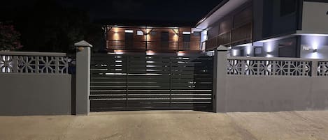 A gated entrance to a modern building with a flat roof and multiple windows.