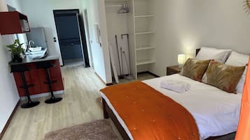 Ein Hotelzimmer mit Bett, Schreibtisch mit Stuhl, Kleiderschrank und Bad.