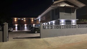 Een modern huis met twee verdiepingen, een overdekte oprit en een toegangshek.