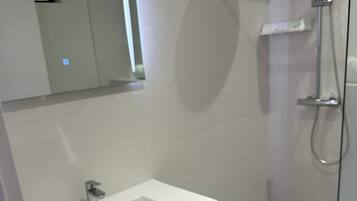 Une salle de bain moderne avec une douche à parois de verre, un lavabo blanc et un miroir au-dessus du lavabo.