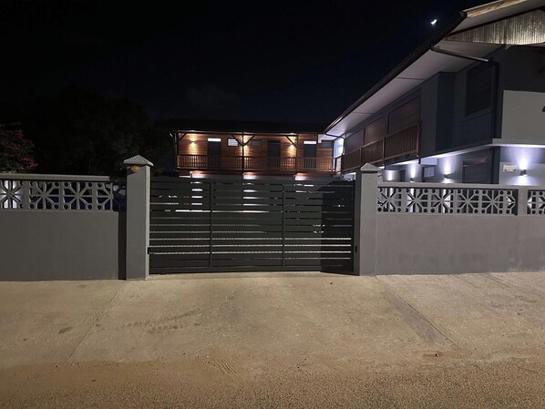 Una entrada protegida por un muro a un edificio moderno con techo plano y múltiples ventanas.