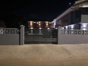 A gated entrance to a modern building with a flat roof and multiple windows.
