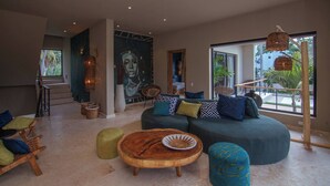 A modern living room with a sectional sofa, a wooden coffee table, and a large window with a view of palm trees. - Coconut Beach House Playa Bonita Las Terrenas Dominican Republic (Las Terrenas)