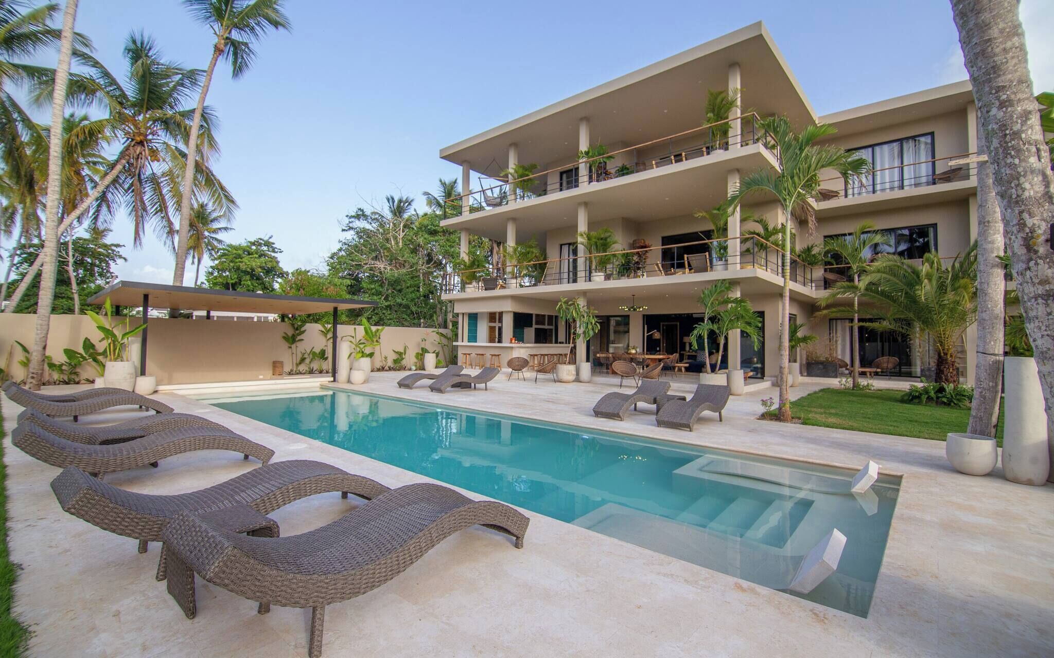 A modern resort with a pool, lounge chairs, and a two-story building with balconies.