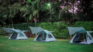 Three camping tents in a grassy field with dense foliage in the background. - Shose Campsite (Moshi)