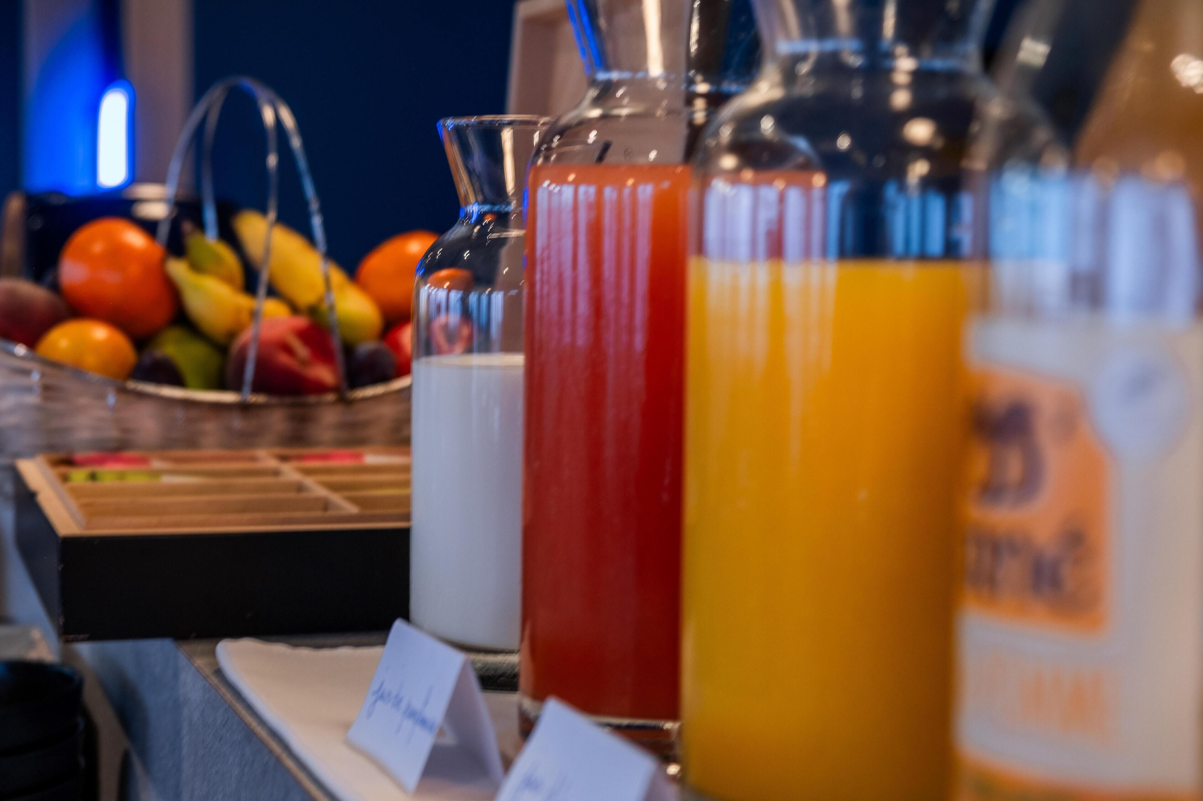 Un assortiment de boissons dans des bouteilles en verre, un panier de fruits et un présentoir à menus.