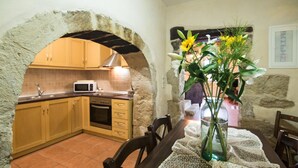 A rustic kitchen with wooden cabinets, a microwave, and a stone archway. - Villa Kourkoulios in Apokoronos (Apokoronas)