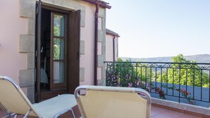 A balcony with two chairs, a wooden door, and a view of greenery and hills. - Villa Kourkoulios in Apokoronos (Apokoronas)